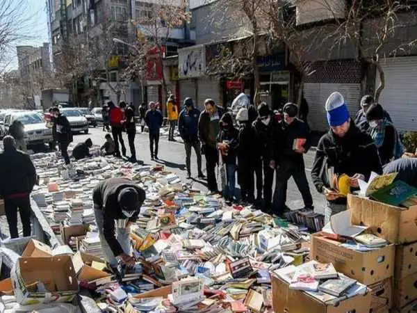 عکس؛ سفر به تاریخ؛ «عابران در حال خرید کتاب از یک دستفروش در خیابان انقلاب»؛ سال 1358